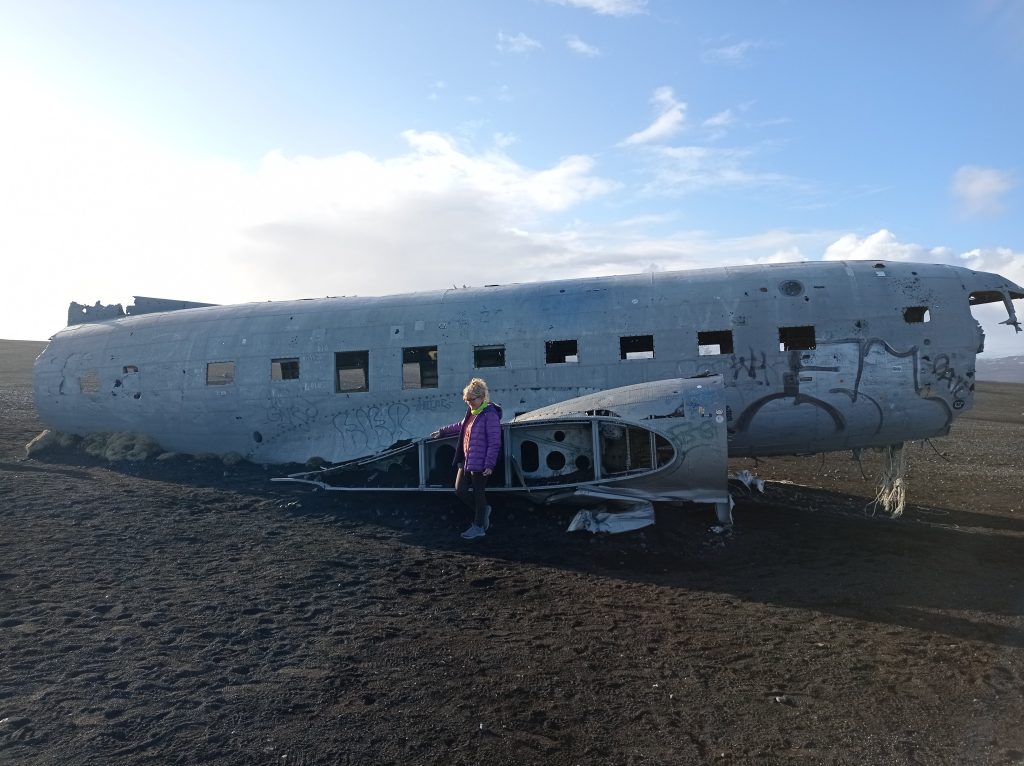 Nicol explorando los restos de un avión en Islandia, un destino emblemático para mujeres que viajan solas, rodeada por la impresionante naturaleza de la tierra de hielo y fuego.